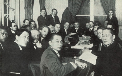 Gezelschap van circa 20 mannen op het Congres van de Anti Imperialisme liga in Brussel in 1927. De mannen zitten rondom een tafel met papier en boeken en Mohammad Hatta zit vooraan.