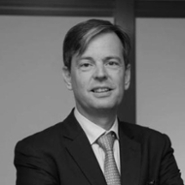 Portret in zwart-wit van een blanke man van middelbare leeftijd die een colbert en een stropdas draagt.