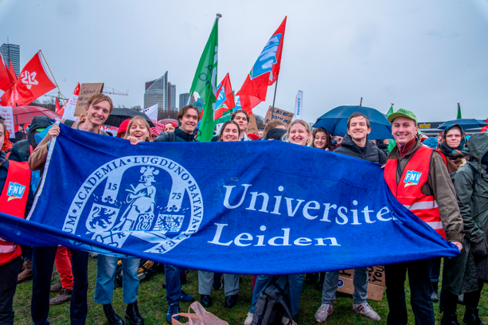 Protestors standing at Malieveld in The Hague holding a large Leiden University banner.