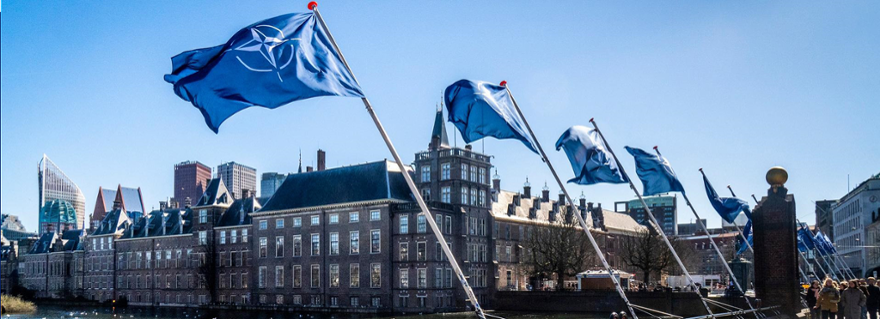 Een rij met NAVO-vlaggen die wapperen naast de Hofvijver in Den Haag.