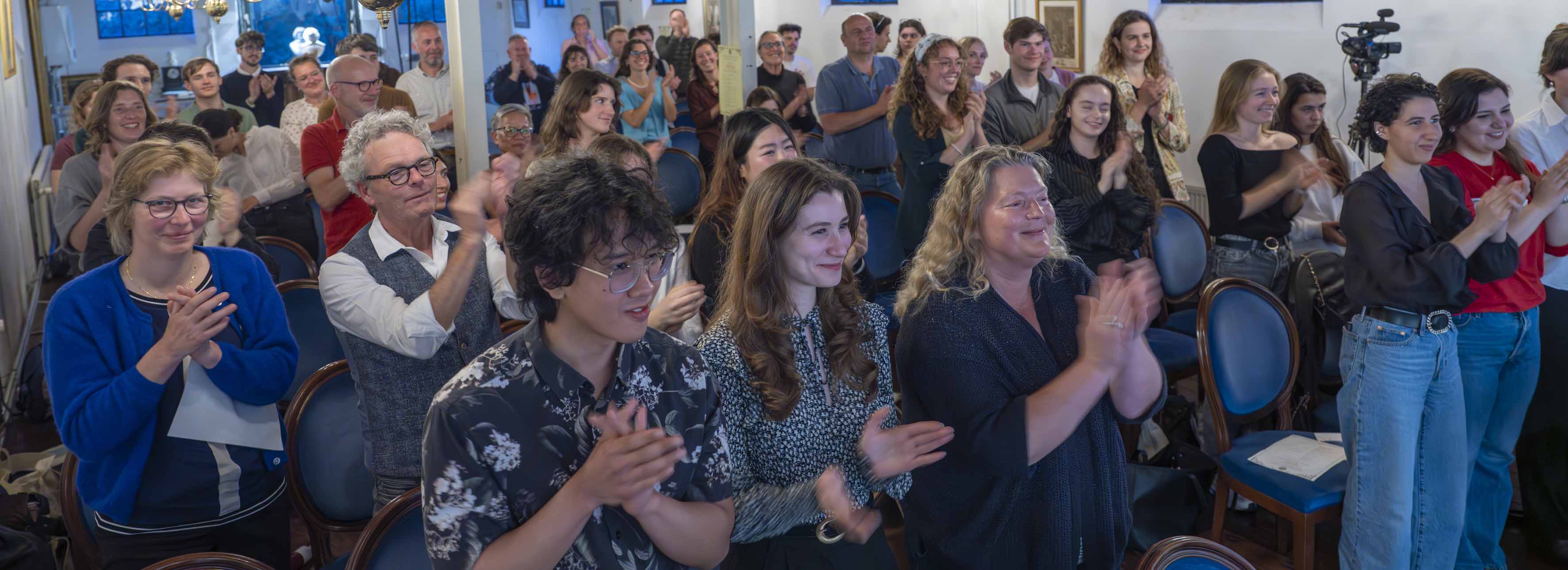 Standing ovation from the audience, smiling faces.