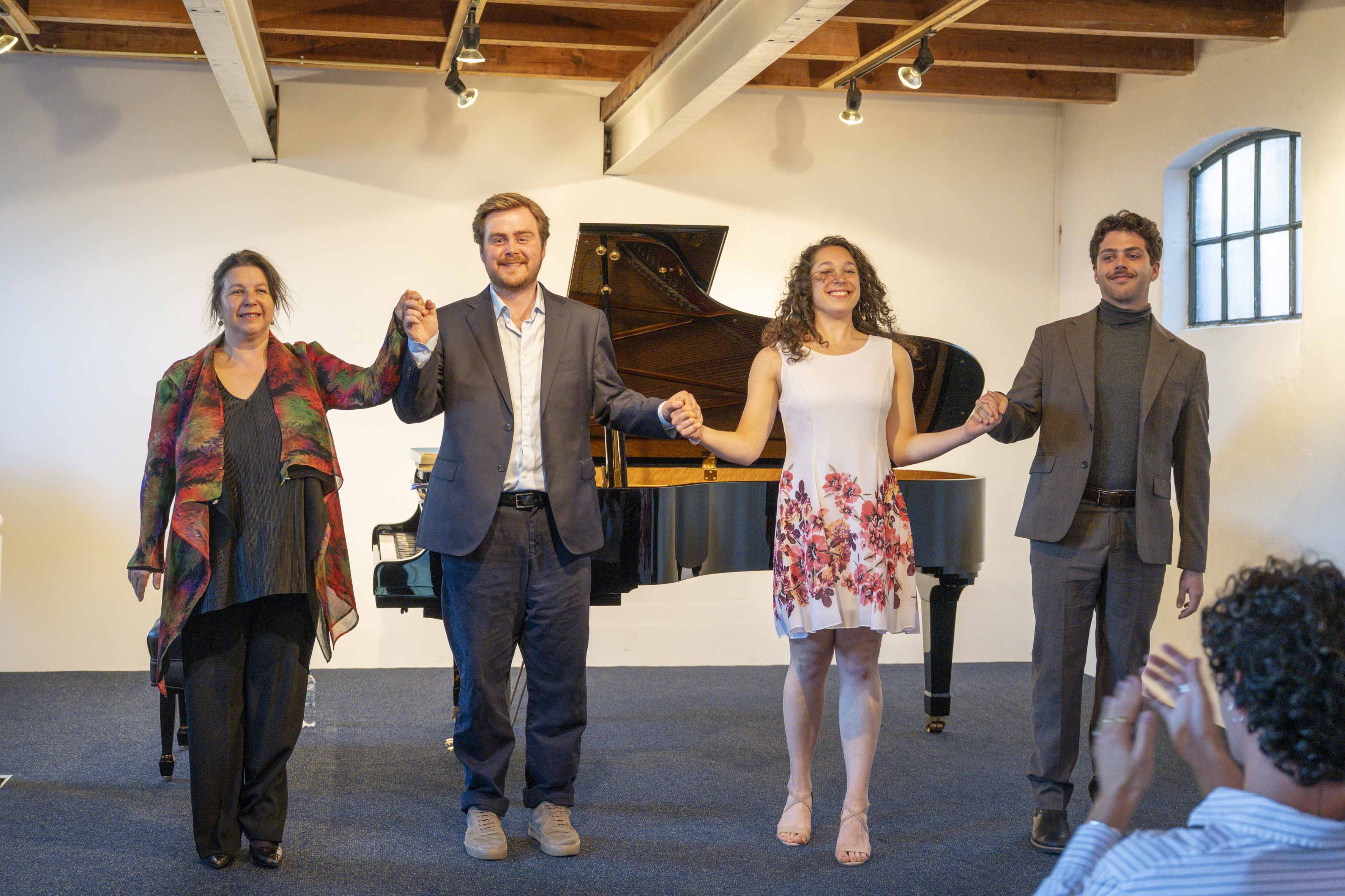 Singing students and pianist hold hands and bow to the audience.