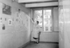 Truus Wijsmuller, board member of the Anne Frank Stichting, removes the plastic covering the pictures in Anne's room before the official opening of the museum. Amsterdam, 3 May 1960.