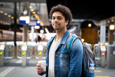 Student with coffee waits for train